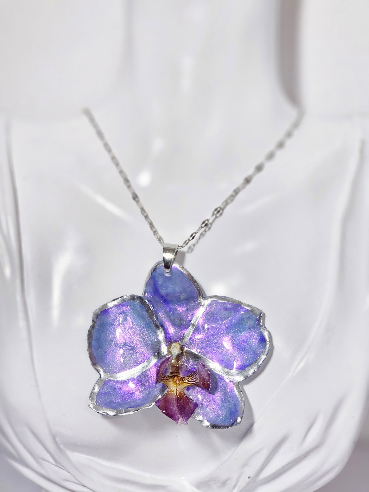 Collar de Orquídea Morada Tornasol artesanal con flor natural preservada; material: acero inoxidable