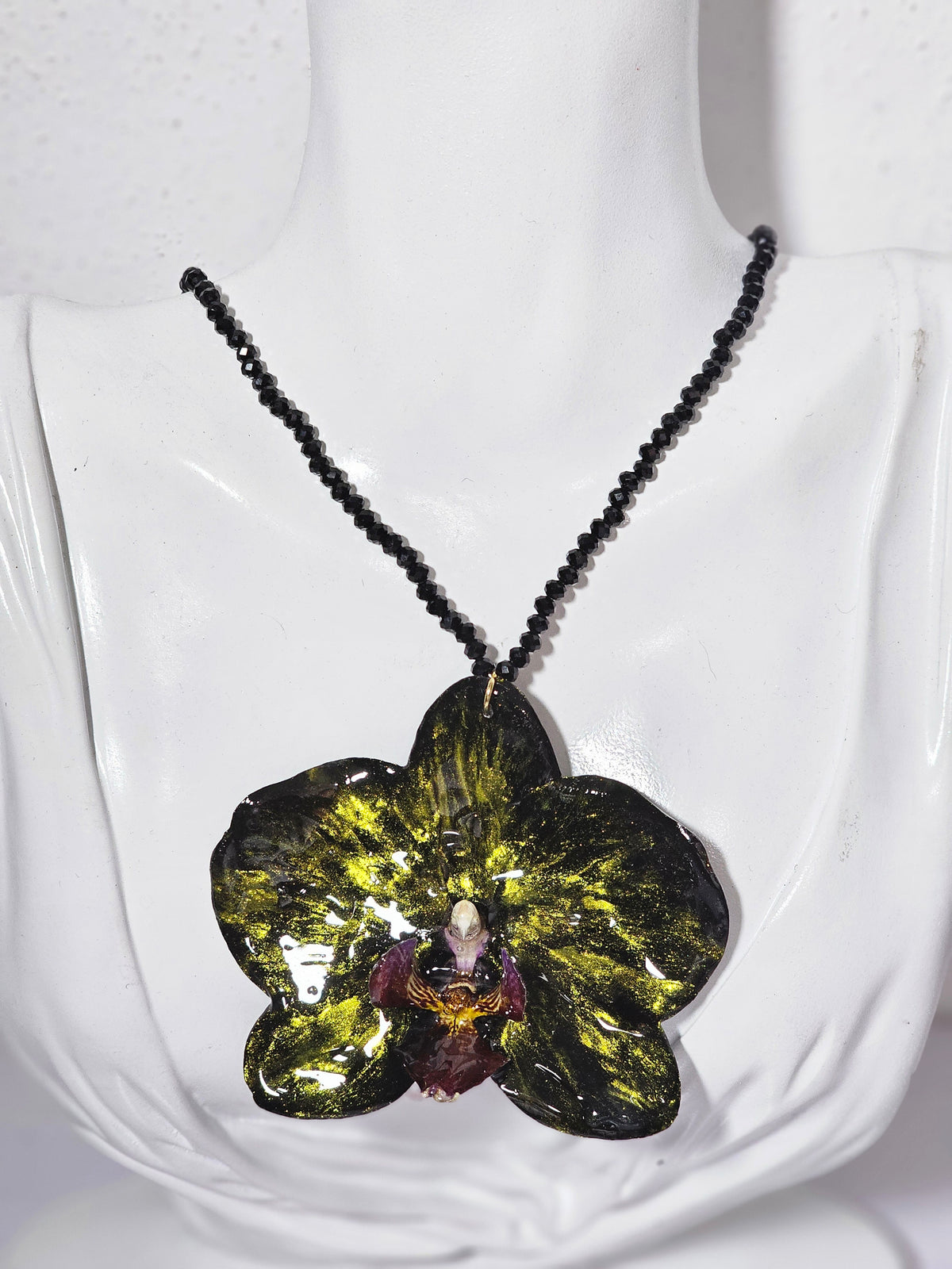 Collar de Orquídea Negra Tornasol artesanal con flor natural preservada; material: acero inoxidable