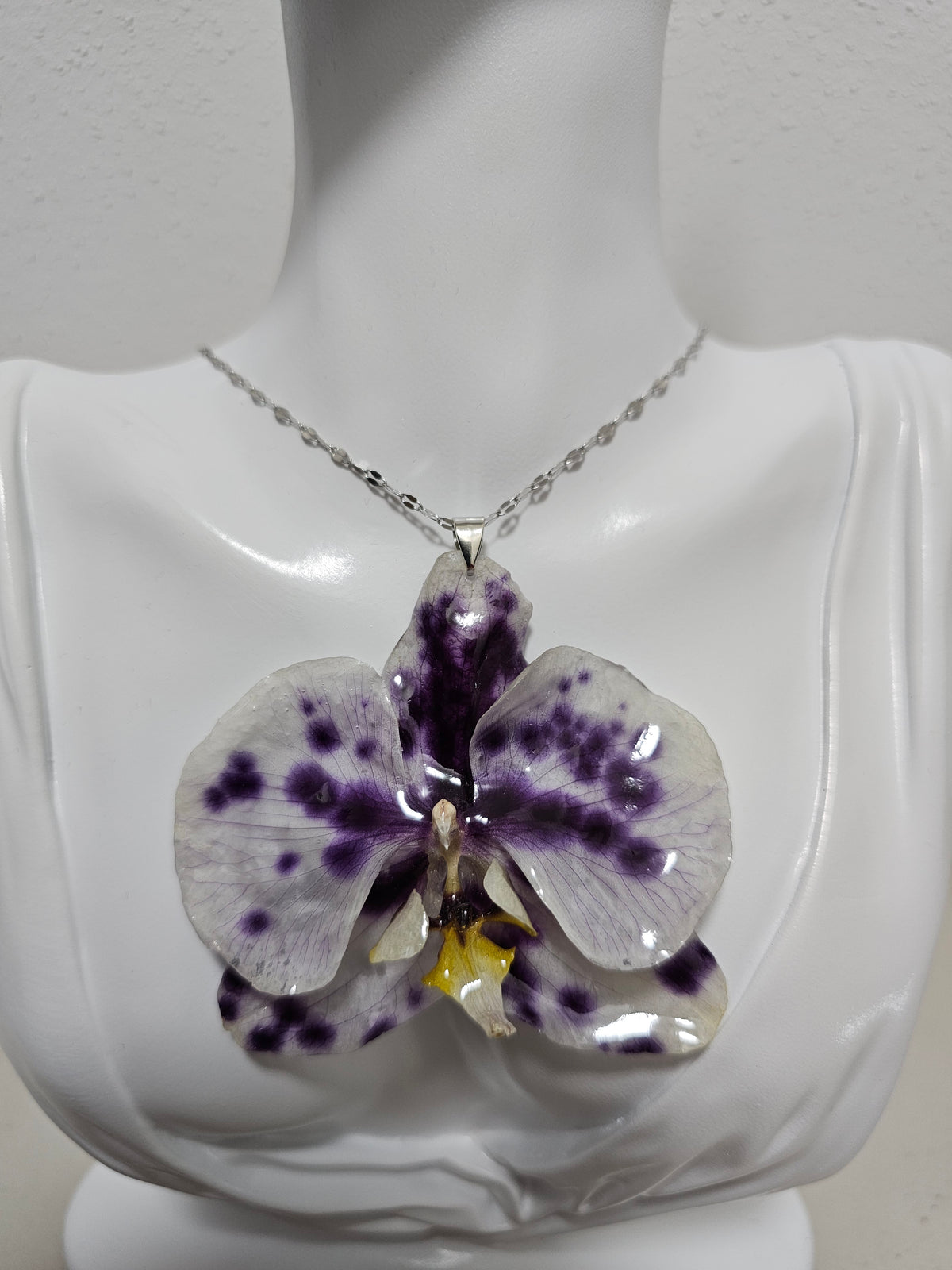 Collar de Orquídea Vaquita artesanal con flor natural preservada; material: acero inoxidable