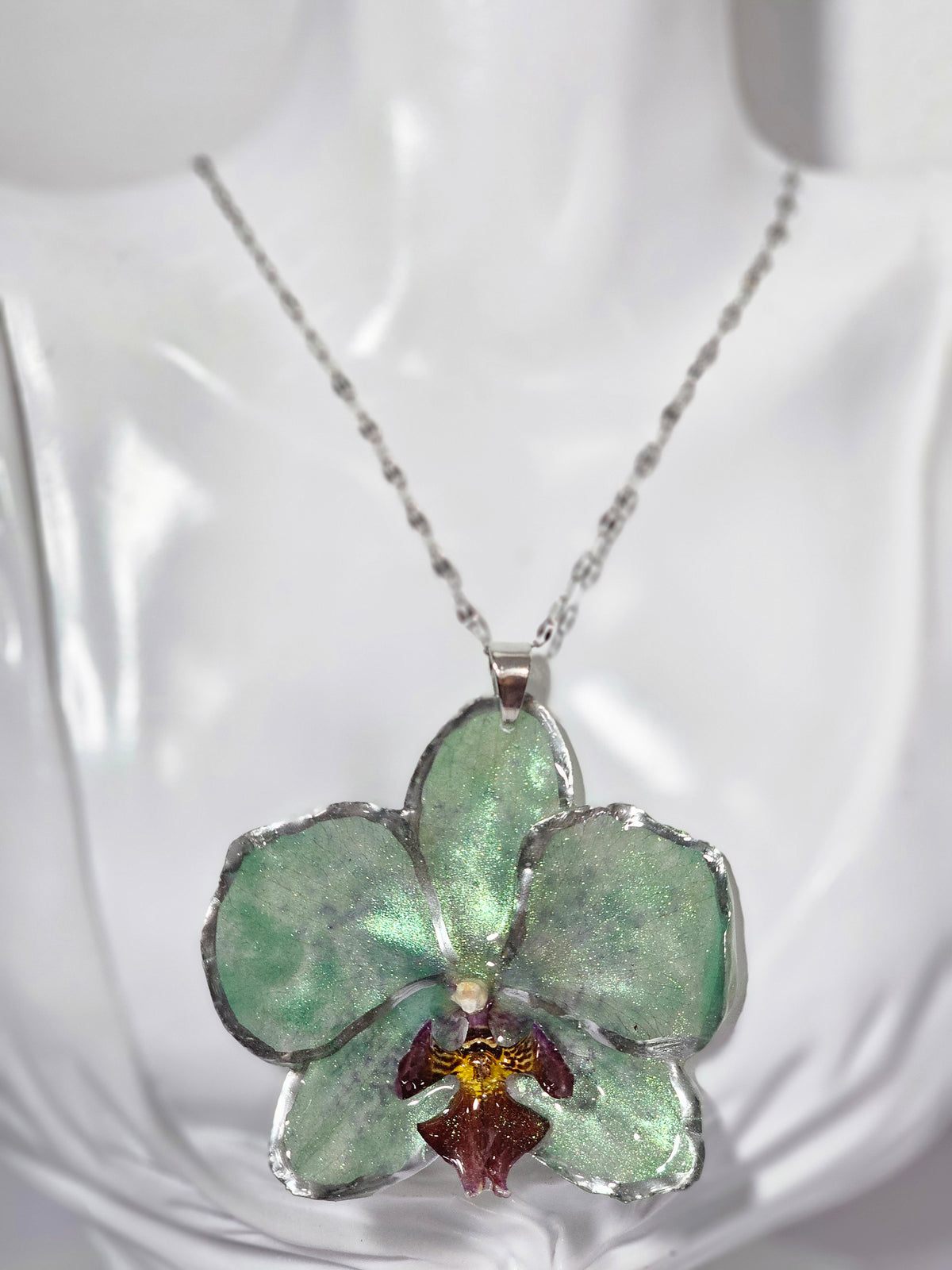 Collar de Orquídea Verde Tornasol artesanal con flor natural preservada; material: acero inoxidable