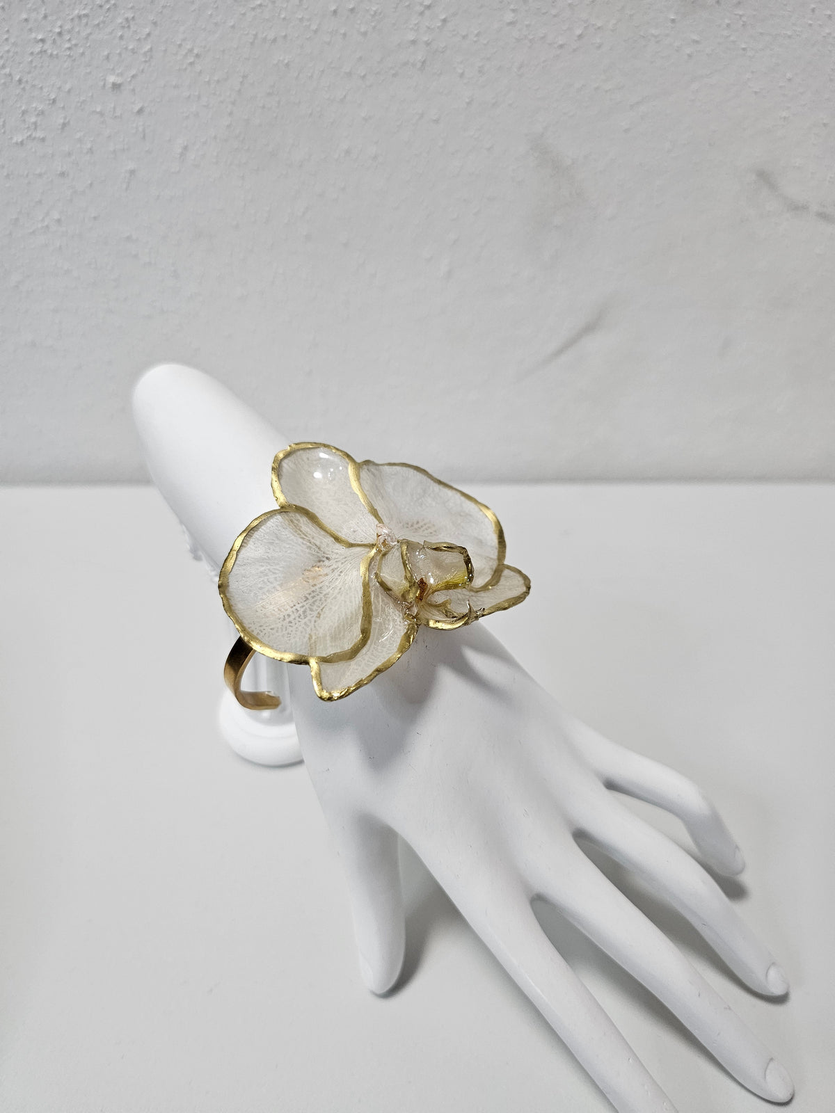 Pulsera de Orquídea Blanca Dorada ISAMOR, vista 2 de la pieza con flor natural encapsulada