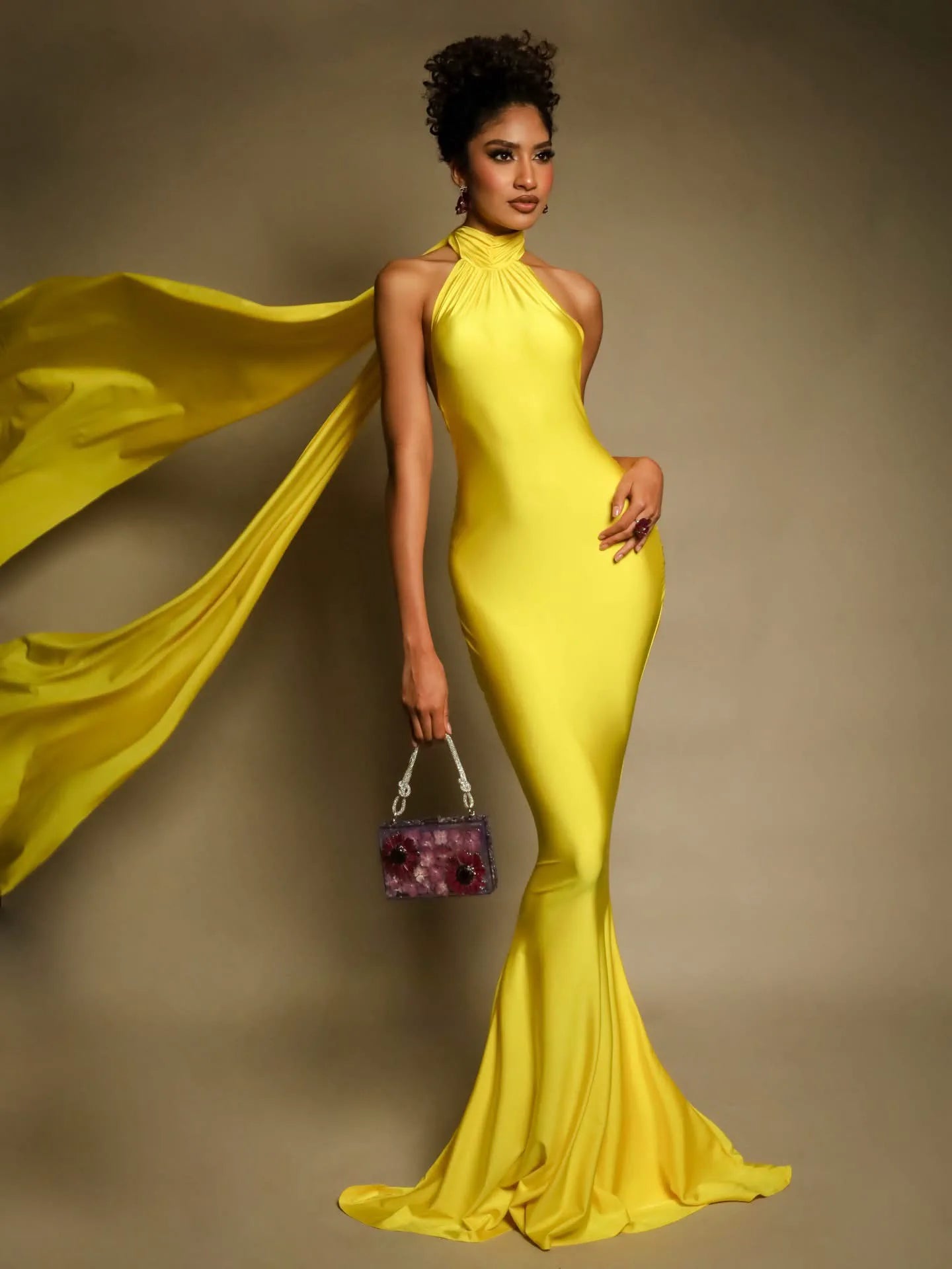 Modelo con vestido amarillo luciendo joyería floral morada y bolso botánico de ISAMOR
